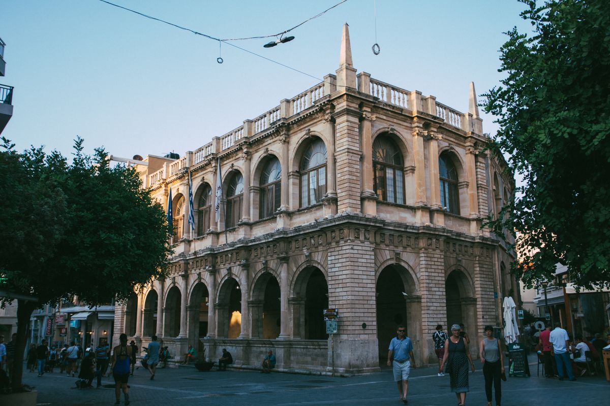 The arcaded Venetian Loggia in Heraklion old town at dusk with people walking the pedestrian street