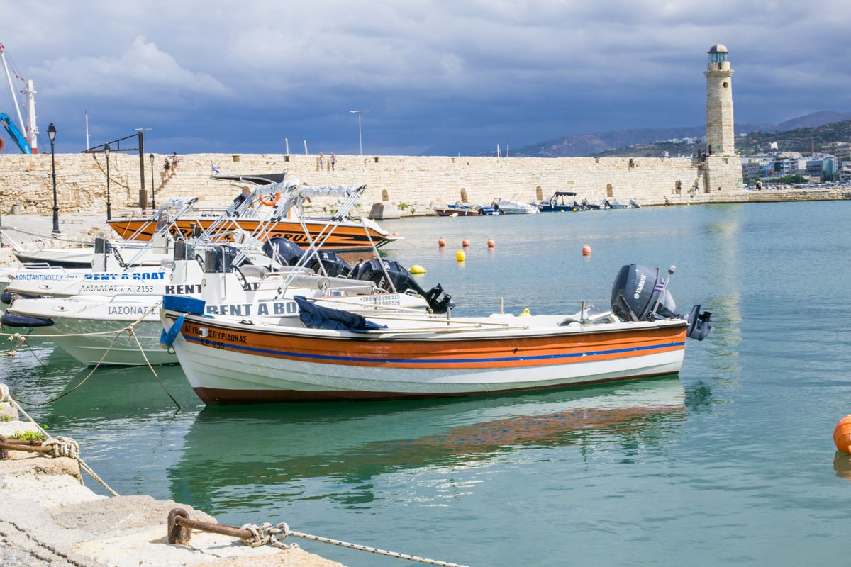 Fishing boats moored in Rethymno's Venetian harbour with the squat round stone lighthouse beyond